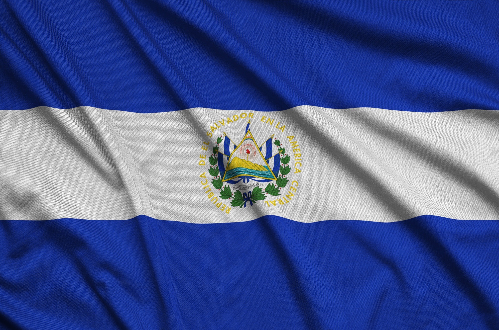 El Salvador flag is depicted on a sports cloth fabric with many folds. Sport team waving banner